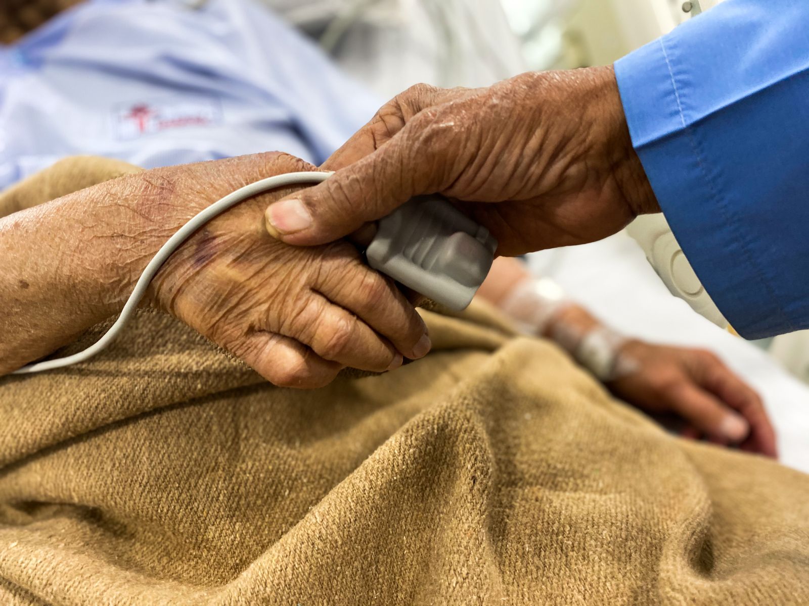 Mão segurando a mão de um paciente idoso no hospital